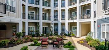 A courtyard with benches and plants in front of a building